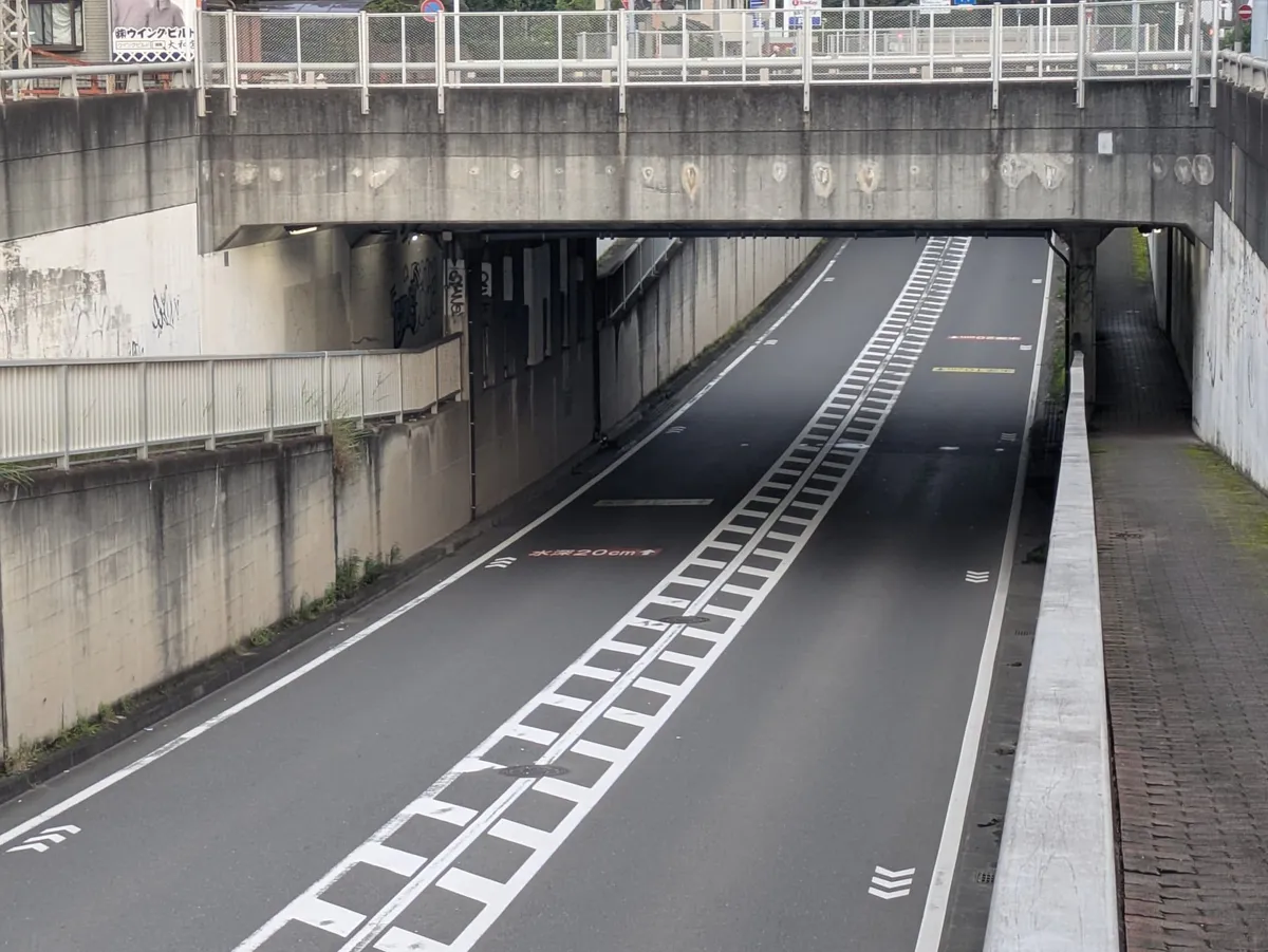 鉄道の下へ下る坂道の路面に、水深の表示が並んでいる